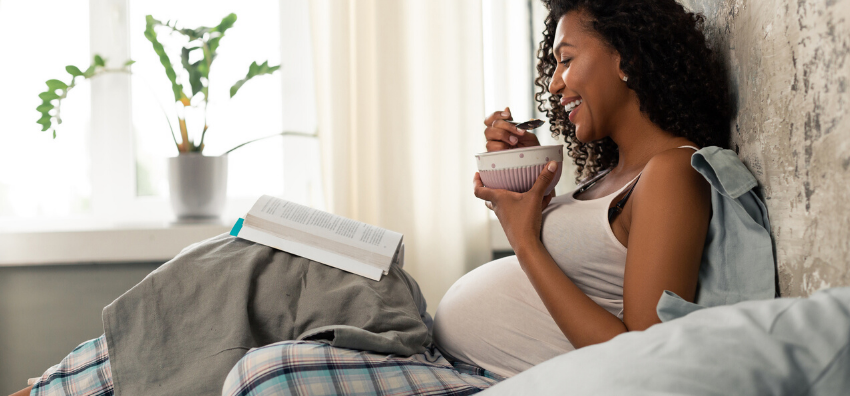 Pregnant woman eating in bed 